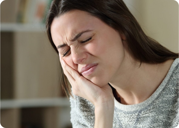 Woman clutching her cheek in discomfort due to a toothache