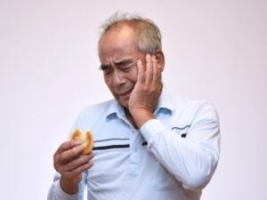 man in pain after biting bagel, possible dental emergency